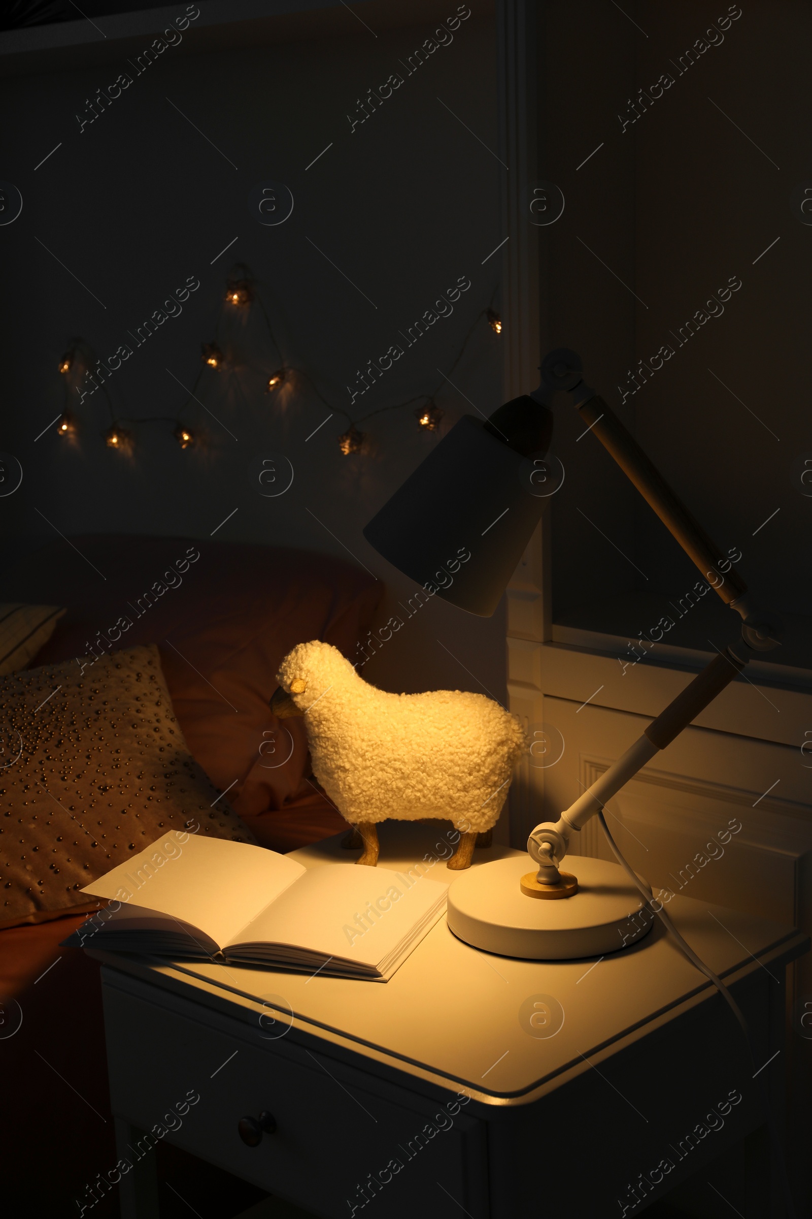 Photo of Lamp glowing on nightstand in cozy bedroom