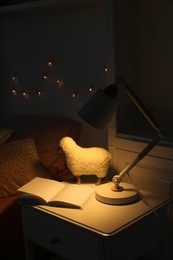 Lamp glowing on nightstand in cozy bedroom