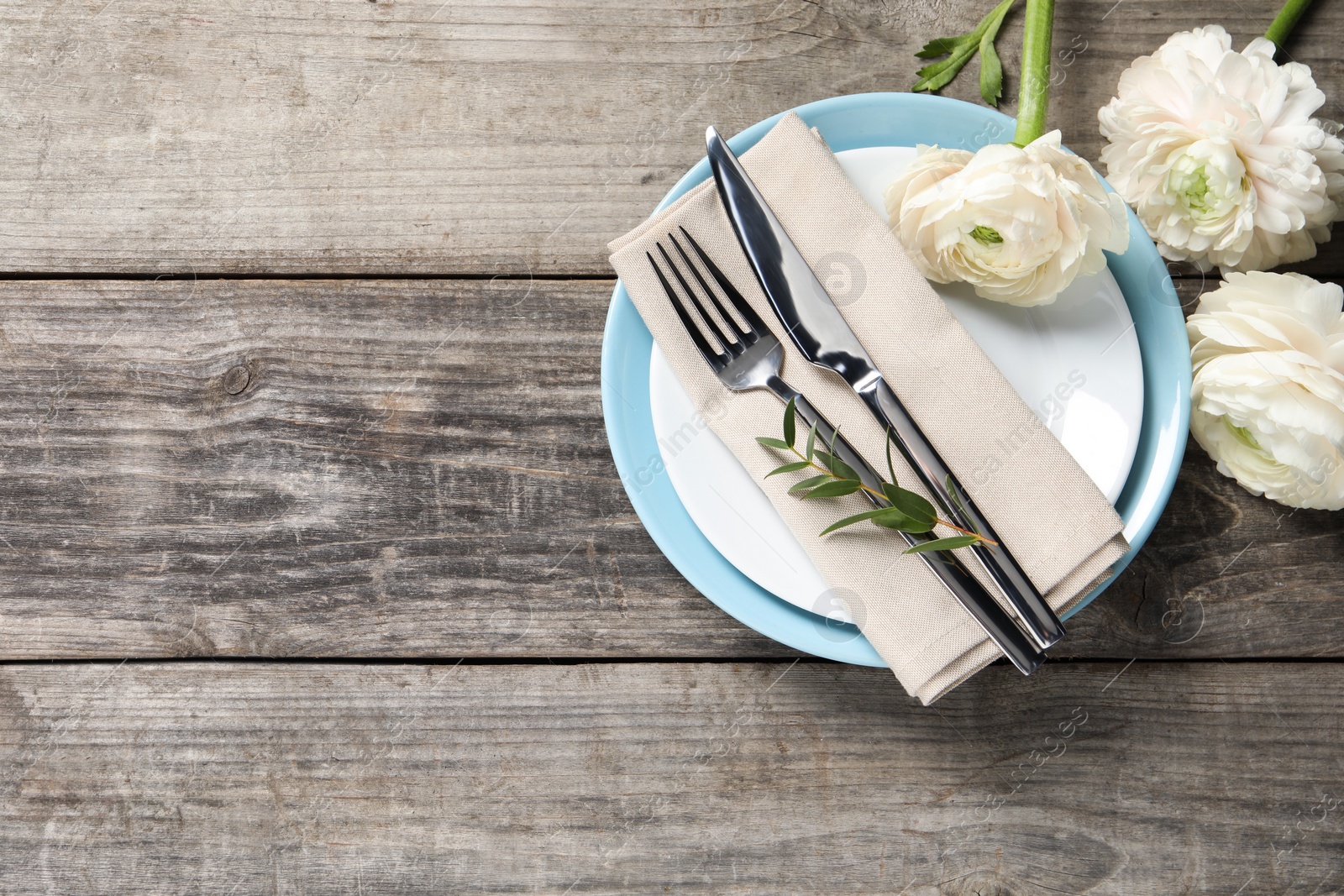 Photo of Stylish table setting with cutlery and flowers on wooden background, flat lay. Space for text