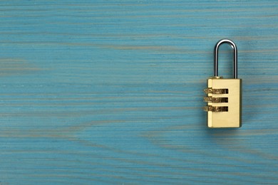 Modern combination lock on light blue wooden table, top view. Space for text