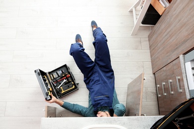 Photo of Male plumber repairing kitchen sink, top view