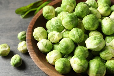 Bowl of fresh Brussels sprouts on grey table, closeup