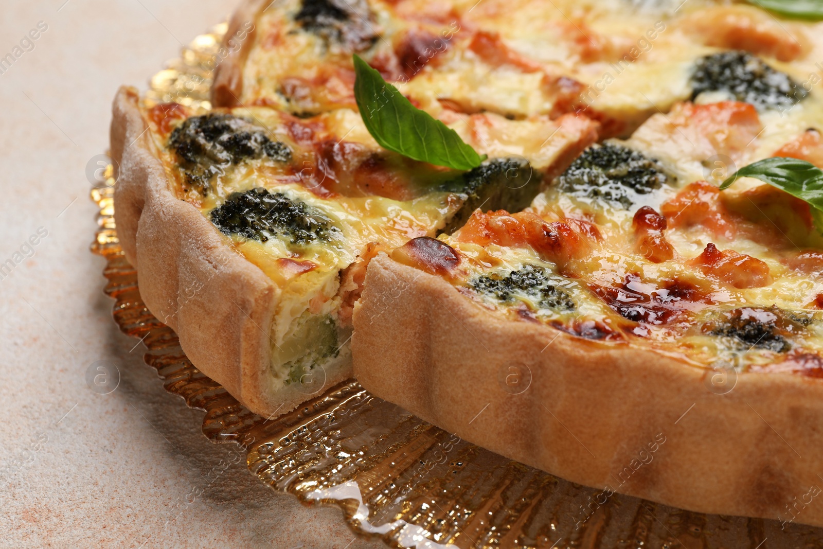 Photo of Delicious homemade quiche with salmon and broccoli on beige table, closeup