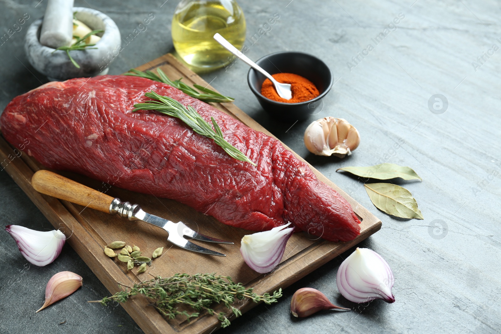 Photo of Piece of raw beef meat and spices on grey table