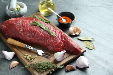 Photo of Piece of raw beef meat and spices on grey table