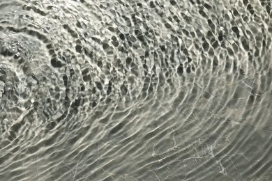 Photo of Rippled surface of clear water on light grey textured background, top view