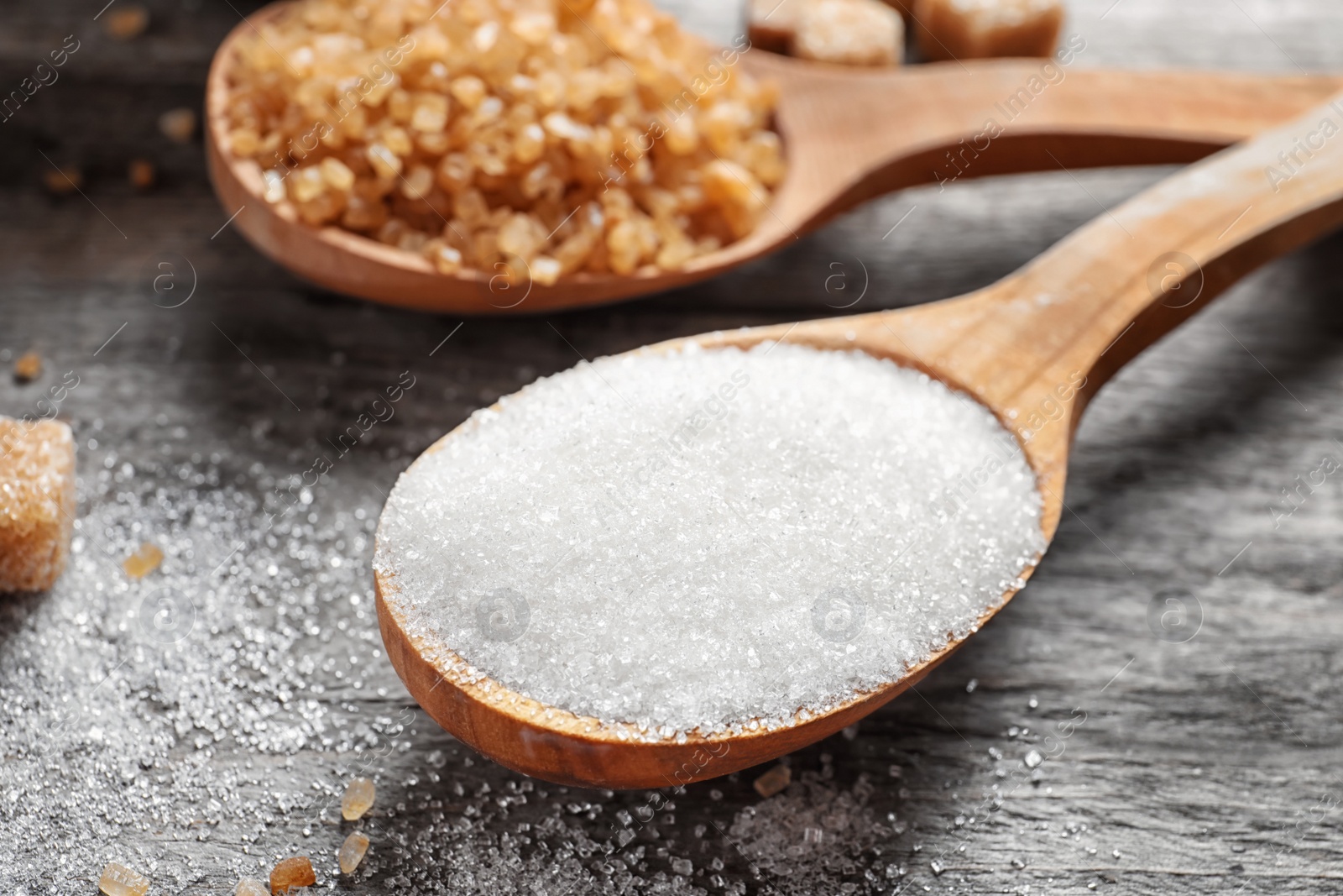 Photo of Spoon with white sugar on wooden table