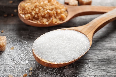 Photo of Spoon with white sugar on wooden table