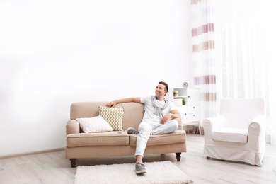 Photo of Happy young man sitting under air conditioner at home