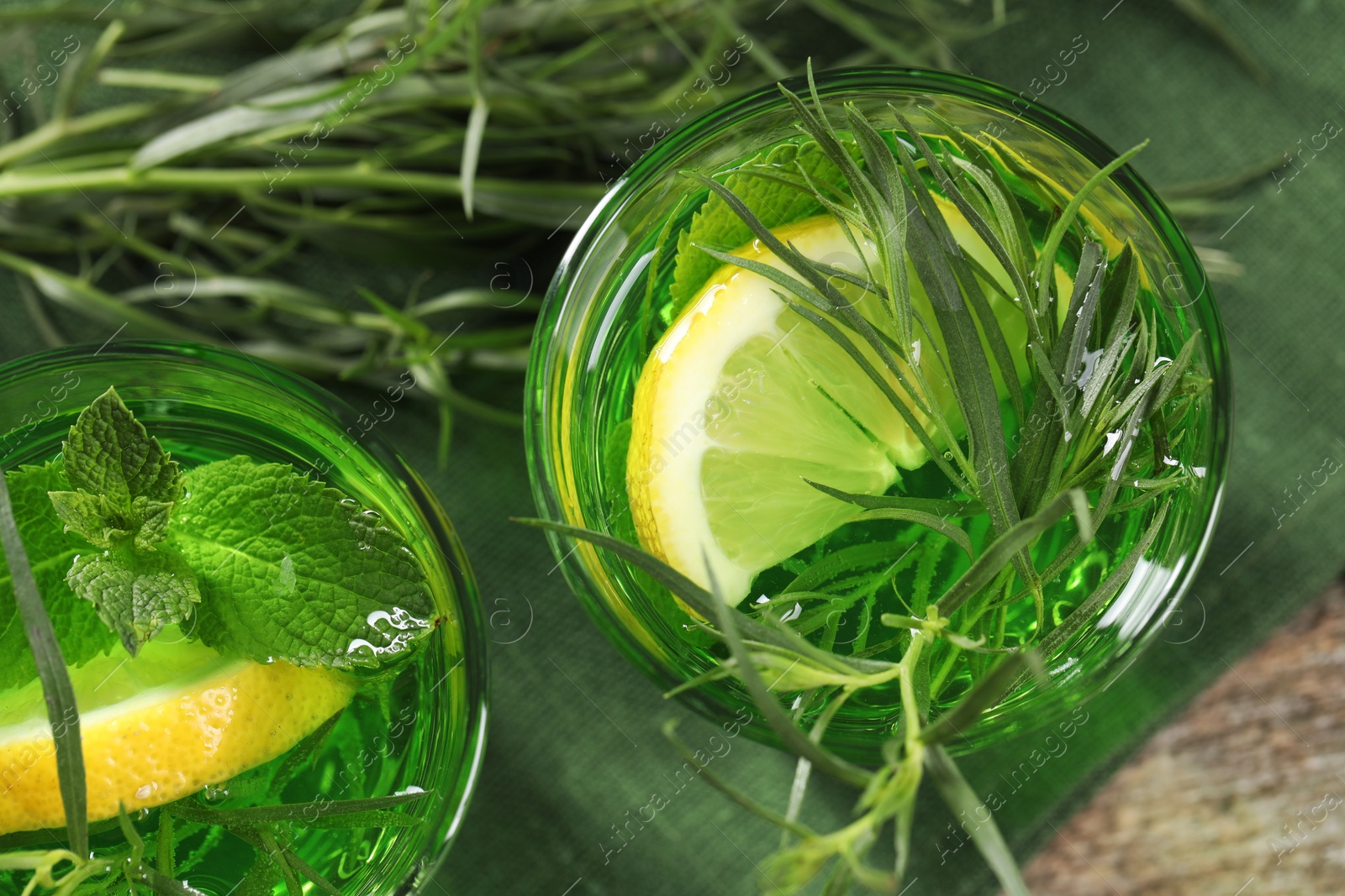 Photo of Glasses of refreshing tarragon drink with lemon slices on table, flat lay