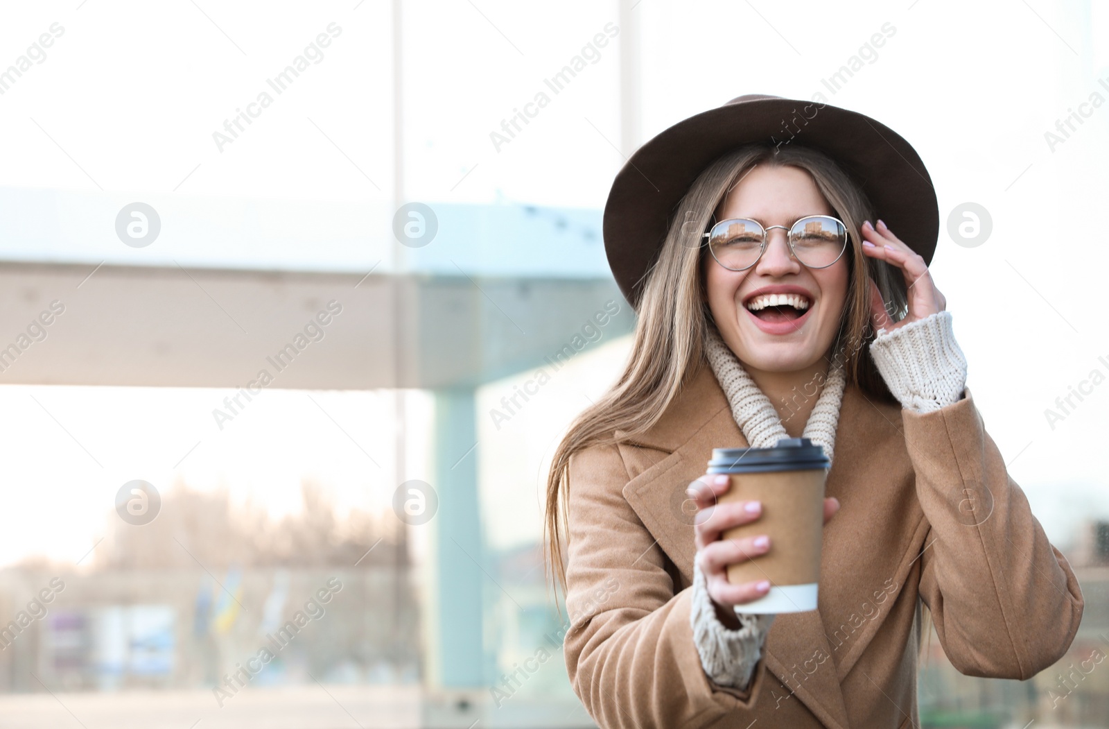 Photo of Young woman with cup of coffee on city street in morning