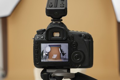 Camera on tripod, armchair and professional lighting equipment in modern photo studio, closeup