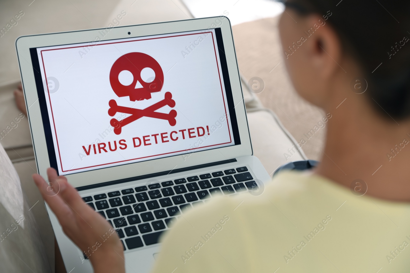 Photo of Woman using laptop with warning about virus attack on screen at home, closeup