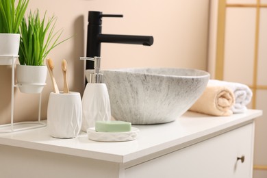 Different bath accessories and personal care products near sink on bathroom vanity