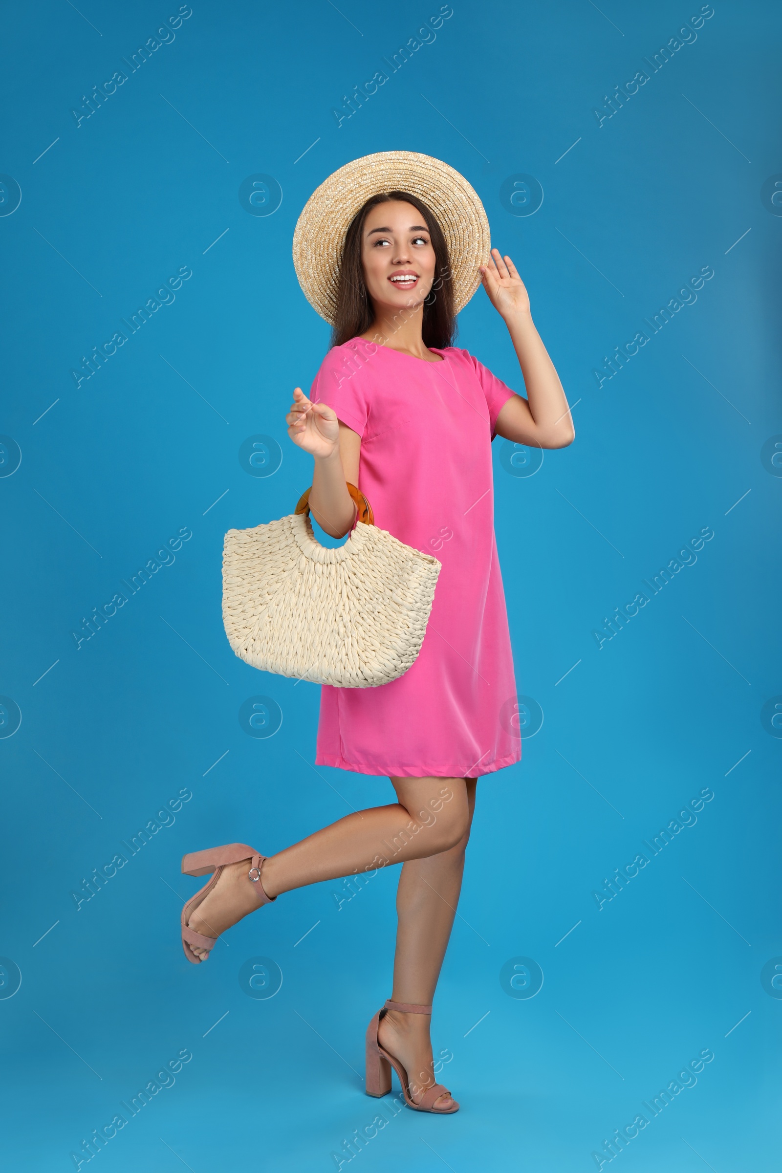 Photo of Young woman with stylish straw bag on light blue background