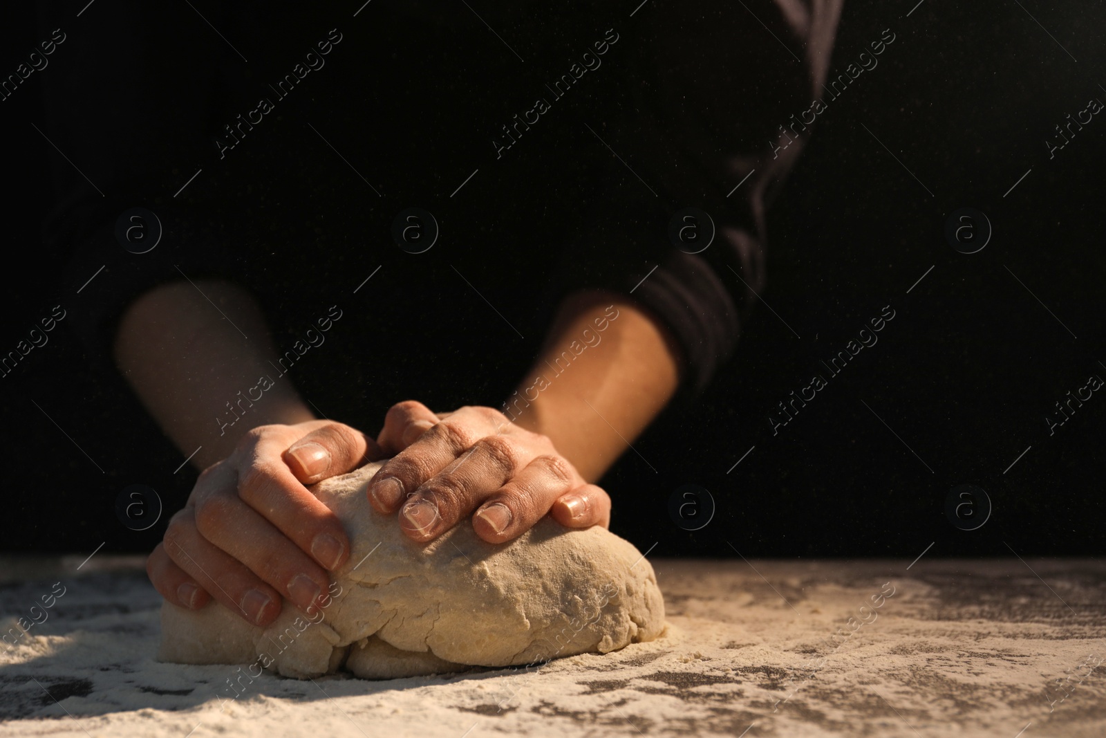 Photo of Making bread. Woman kneading dough at table on dark background, closeup. Space for text