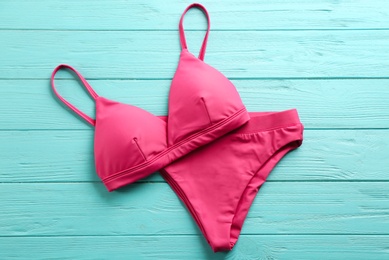 Photo of Beautiful pink bikini on light blue wooden background, top view