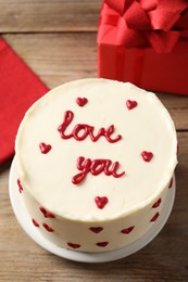 Photo of Bento cake with text Love You and gift box on wooden table, above view. St. Valentine's day surprise