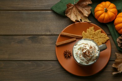 Photo of Flat lay composition of tasty pumpkin spice latte with whipped cream in cup on wooden table. Space for text