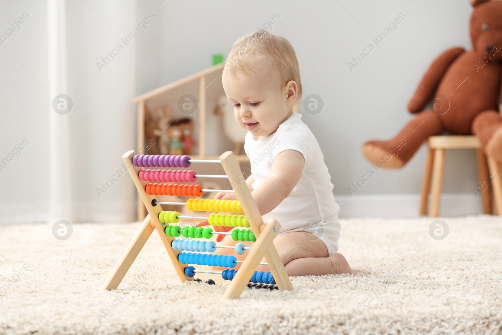 Photo of Children toys. Cute little boy playing with wooden abacus on rug at home