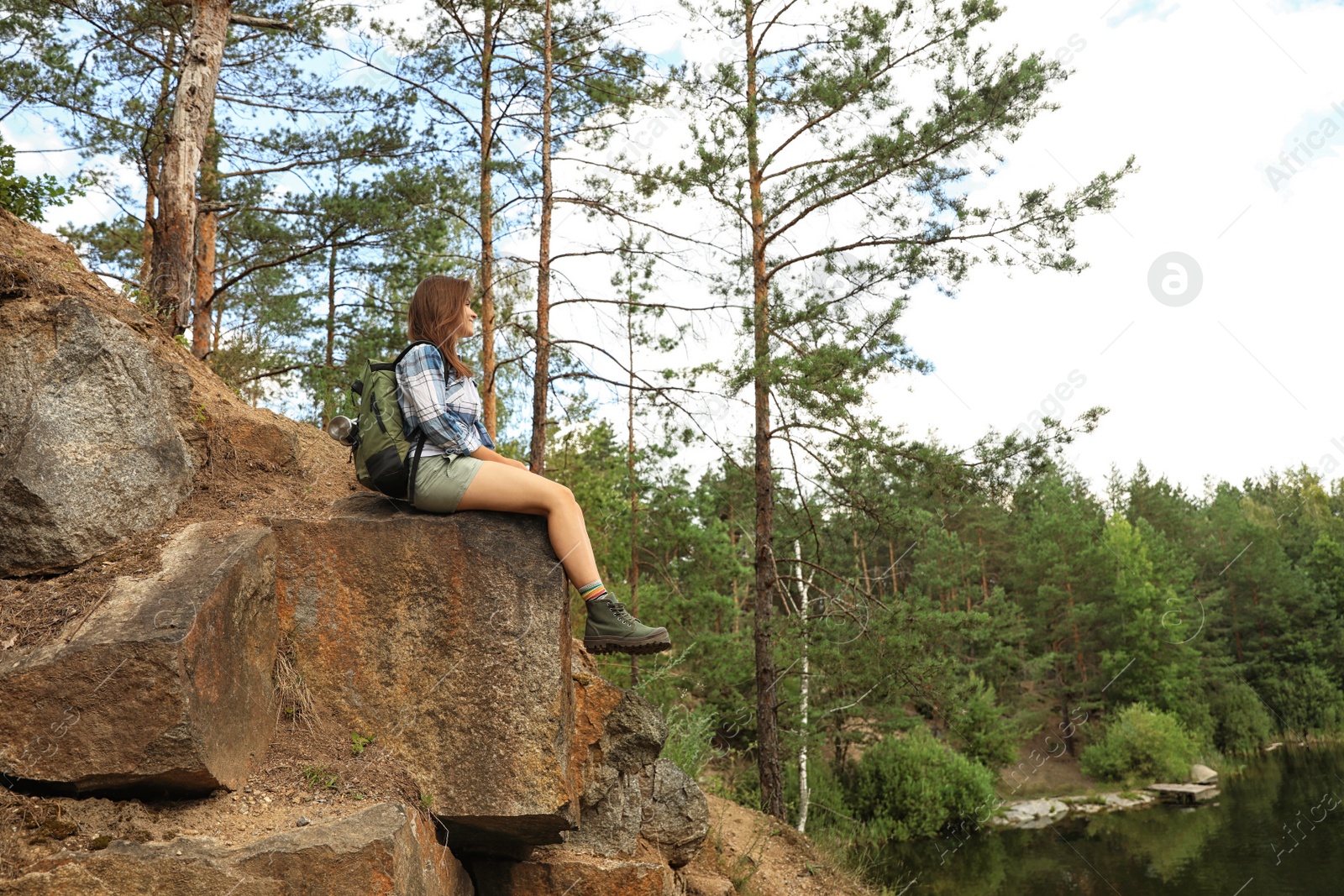 Photo of Young woman on rocky mountain near forest. Camping season