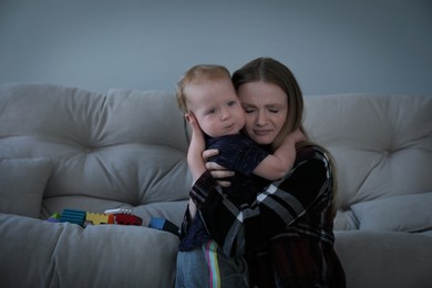 Photo of Depressed single mother hugging her child in living room