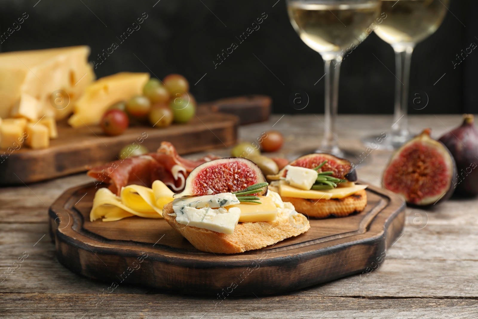 Photo of Sandwiches with ripe figs and delicious products on wooden board