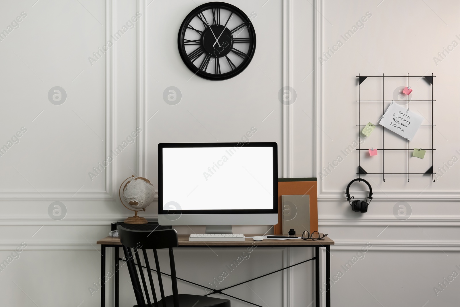 Photo of Stylish workspace with computer and stationery on wooden desk near white wall indoors