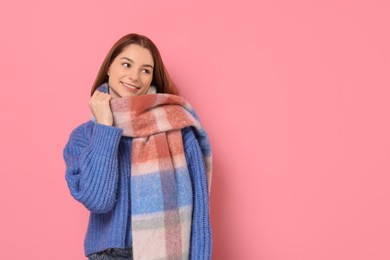 Beautiful woman in warm scarf on pink background, space for text