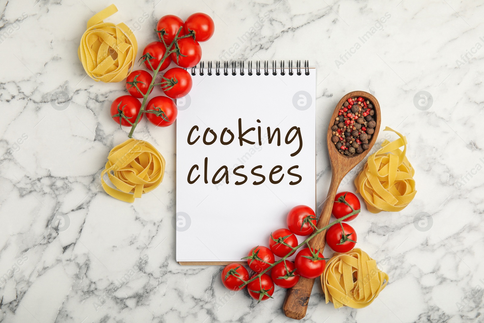 Image of Notebook with inscription Cooking Classes, raw pasta, tomatoes and spices on white marble table, flat lay