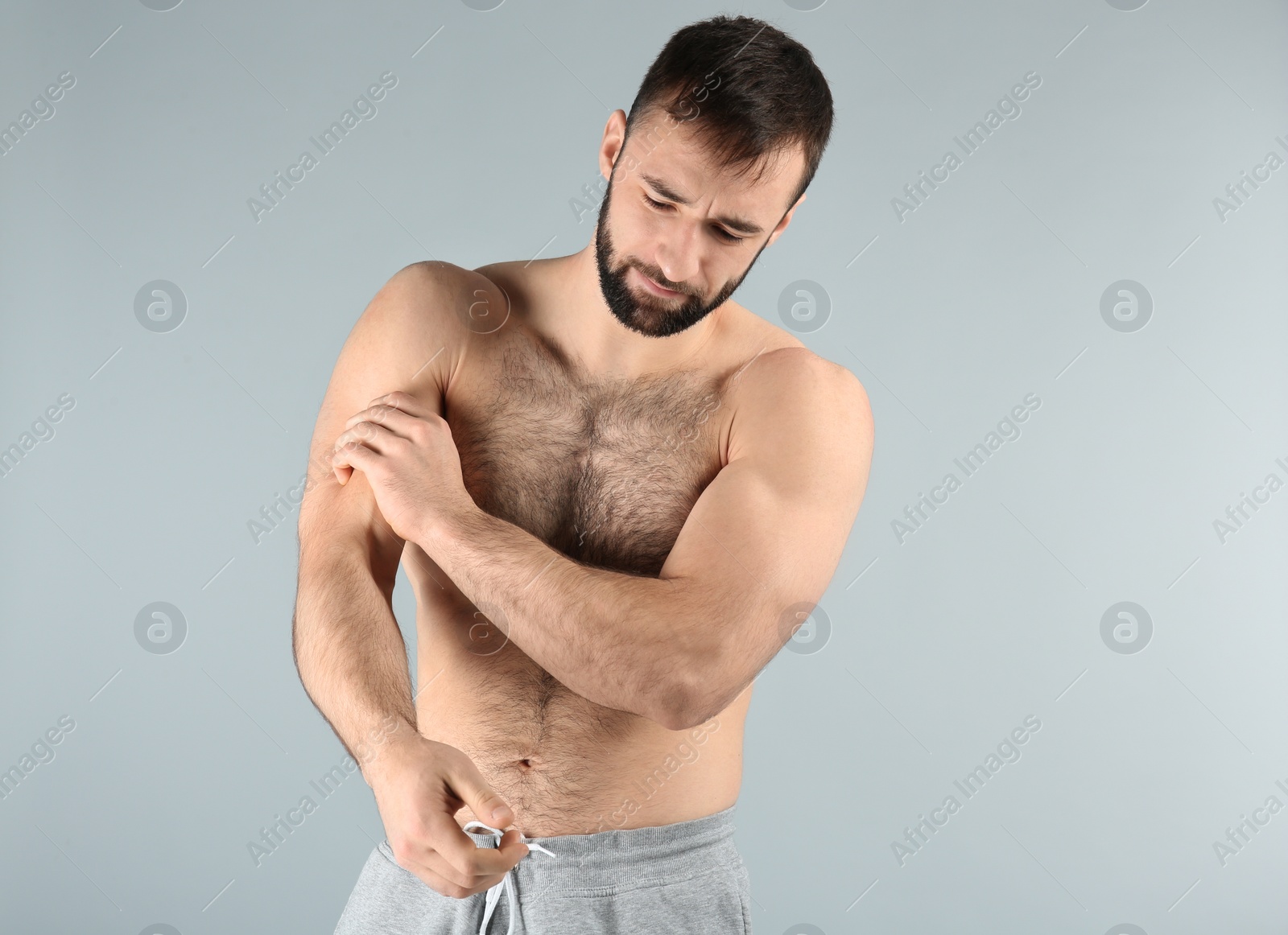 Photo of Young man suffering from pain in arm on light background