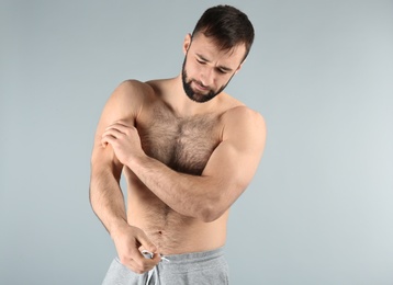 Young man suffering from pain in arm on light background