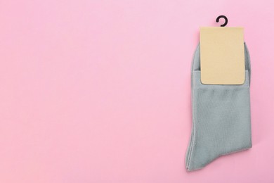 Photo of Pair of grey cotton socks on light pink background, top view. Space for text