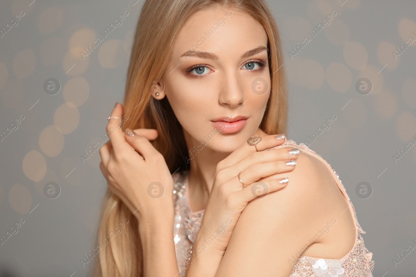 Photo of Beautiful young woman with shiny manicure on blurred background. Nail polish trends