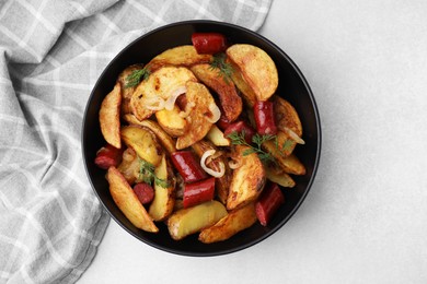 Photo of Delicious baked potato with thin dry smoked sausages, onion and dill in bowl on gray table, top view