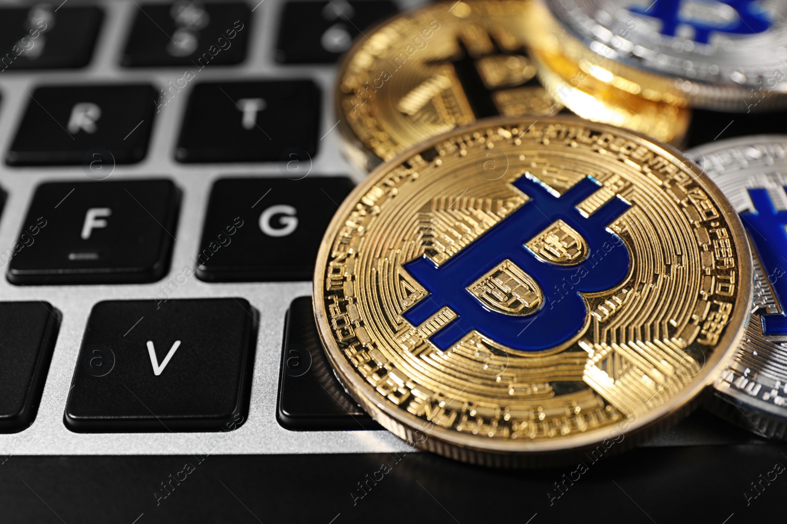 Photo of Golden and silver bitcoins on computer keyboard, closeup. Space for text