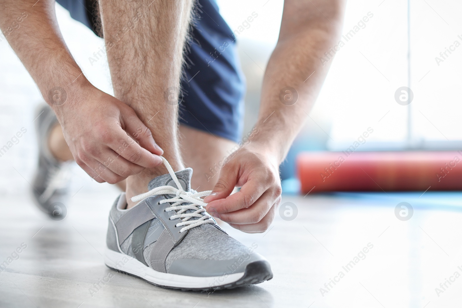 Photo of Man putting on training shoes indoors, closeup