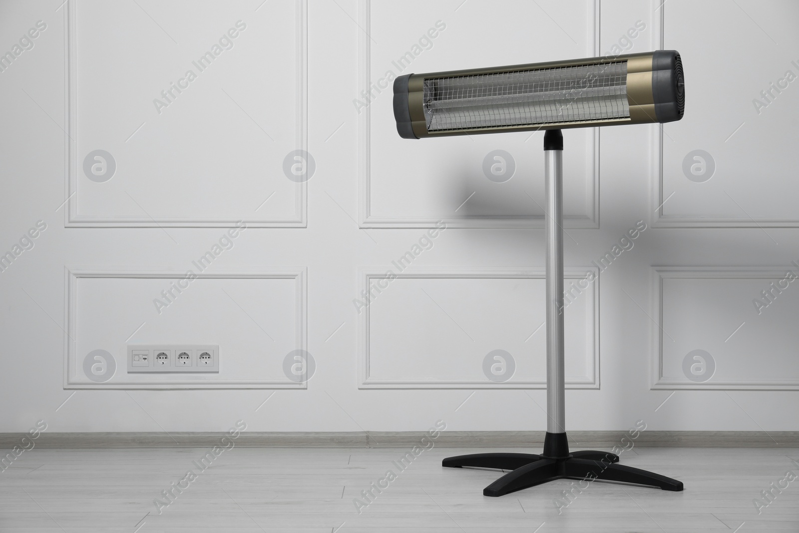 Photo of Modern electric infrared heater near white wall indoors, space for text