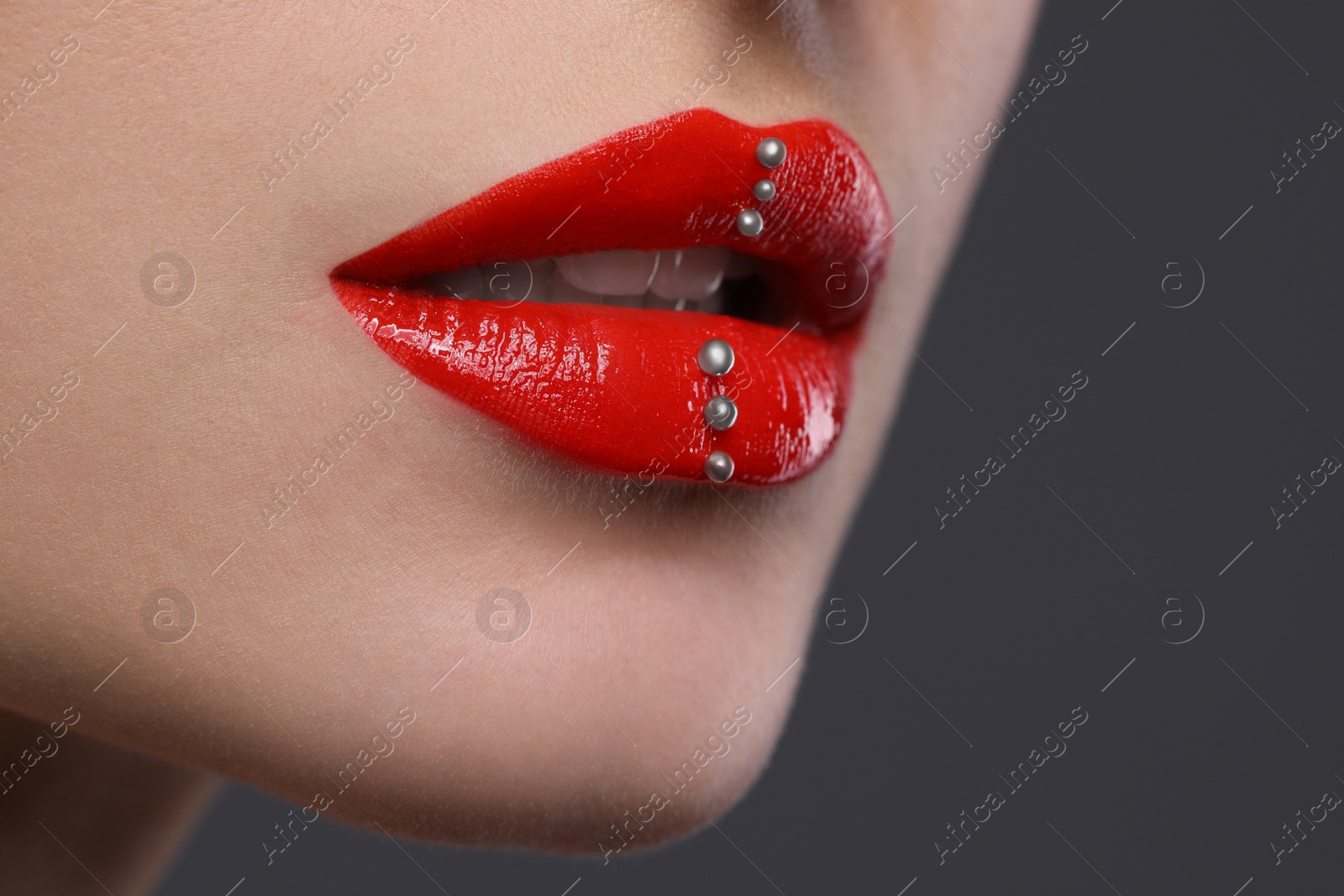 Photo of Young woman with red lips makeup on grey background, closeup