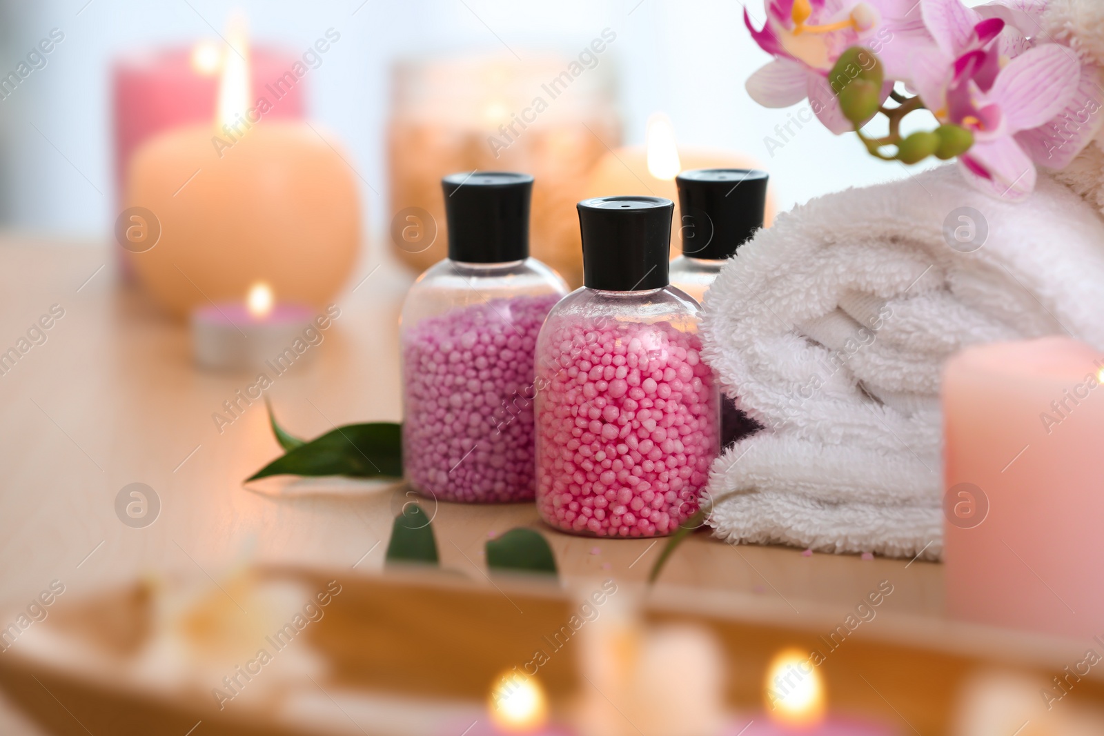 Photo of Bottles with cosmetic beads and towel on table, closeup. Spa salon