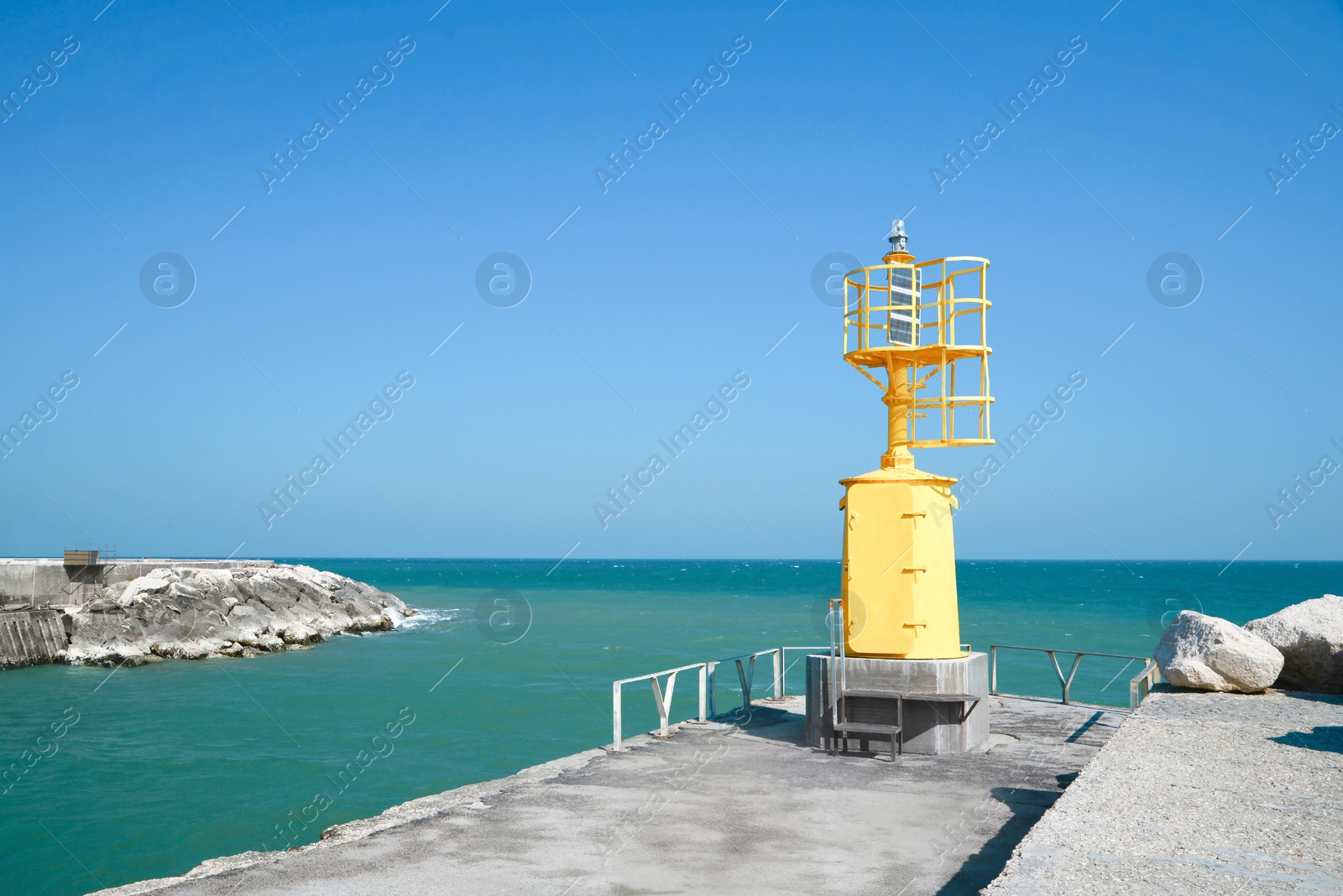 Photo of Yellow navigational aid beacon with solar battery on pier