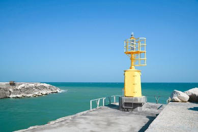 Yellow navigational aid beacon with solar battery on pier
