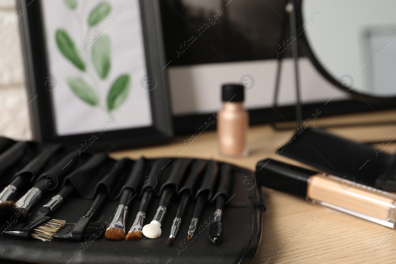 Photo of Set of makeup brushes and cosmetic on wooden dressing table, closeup