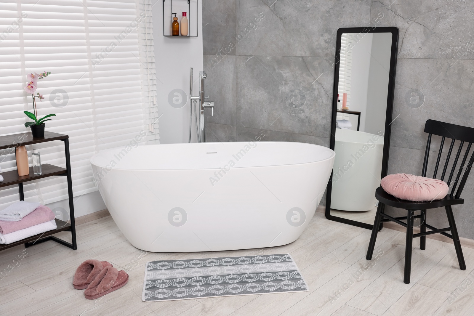 Photo of Stylish bathroom interior with soft bath mat and tub