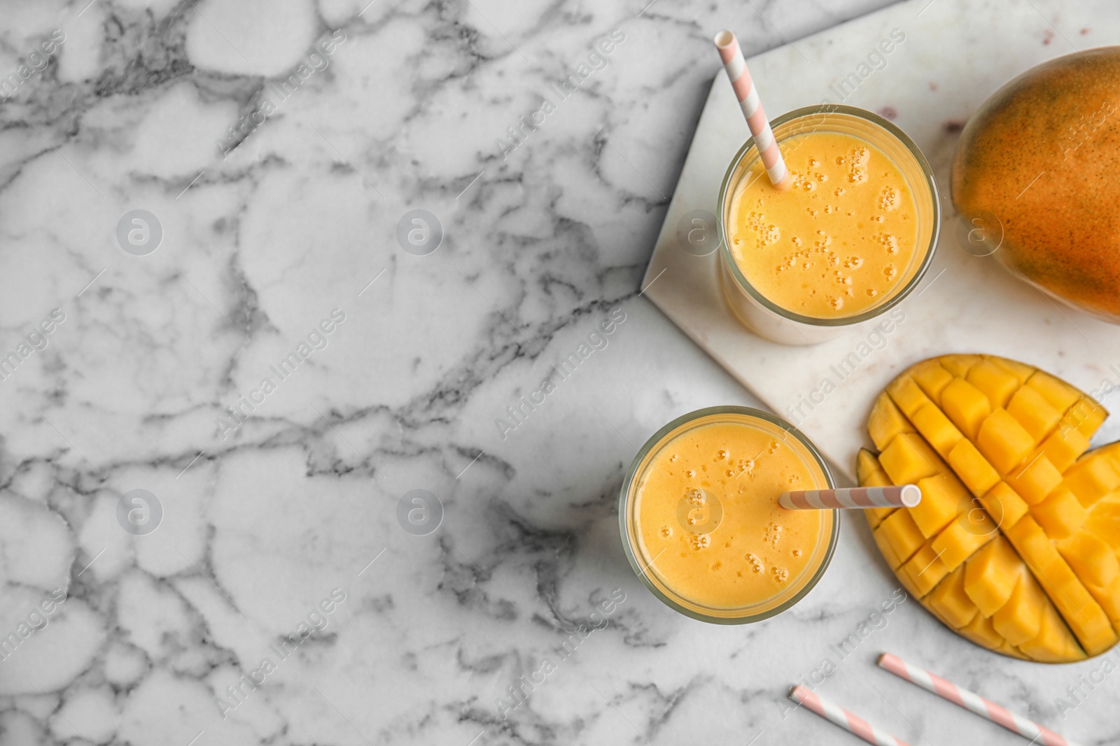 Photo of Glasses of fresh mango drink and fruits on table, top view. Space for text