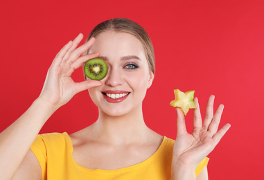Photo of Young woman with cut kiwi and carambola on red background. Vitamin rich food
