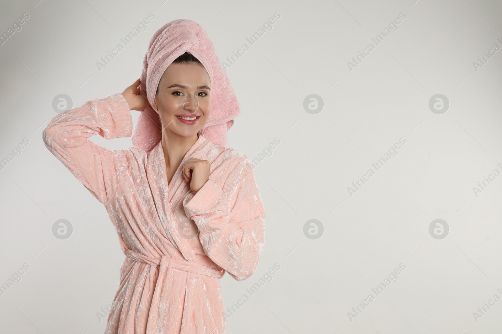 Photo of Beautiful young woman in bathrobe on light background. Space for text