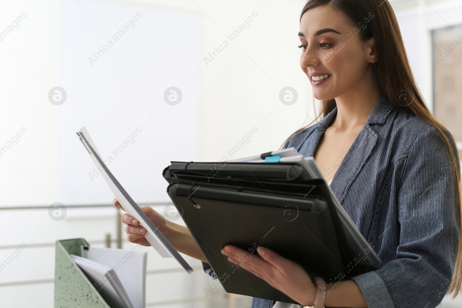 Photo of Young woman working with documents in office