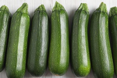 Photo of Raw ripe zucchinis on white wooden table, flat lay