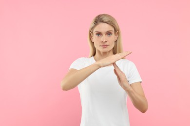 Photo of Woman showing time out gesture on pink background. Stop signal